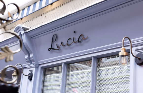 Close-up of the 'Lucia' sign on a stylishly designed exterior with elegant lighting fixtures