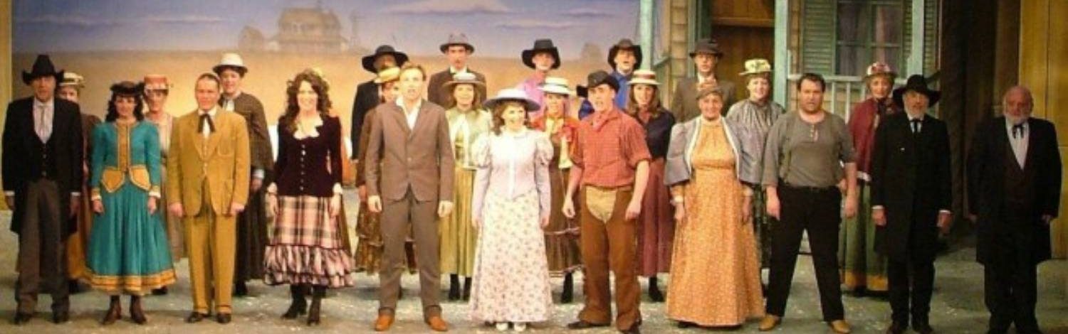 Cast in period costumes on stage