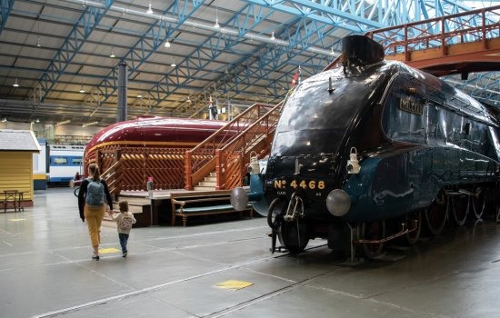A woman walks by a vintage train displayed in a museum, showcasing historical transportation