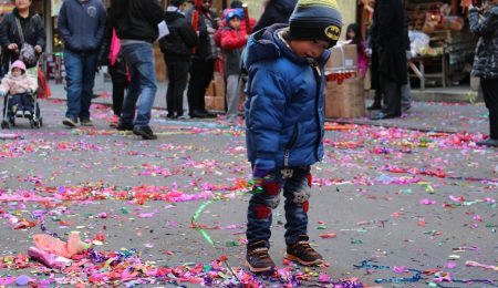 Child in winter clothes amid street confetti
