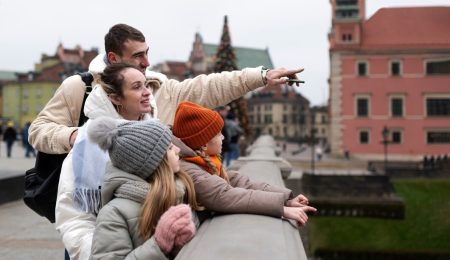 A family is gathered on a bridge, looking curiously at an unseen object below