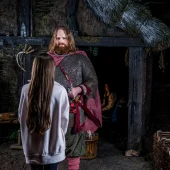 A visitor interacts with a Viking actor inside a historically themed setting at the Jorvik Viking Centre