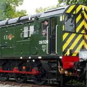 Green train engine with a smiling conductor