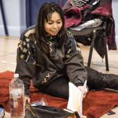 Student sitting and reading on a mat