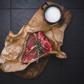 Raw steak with rosemary and salt on paper