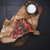 Raw steak and rosemary on wood board